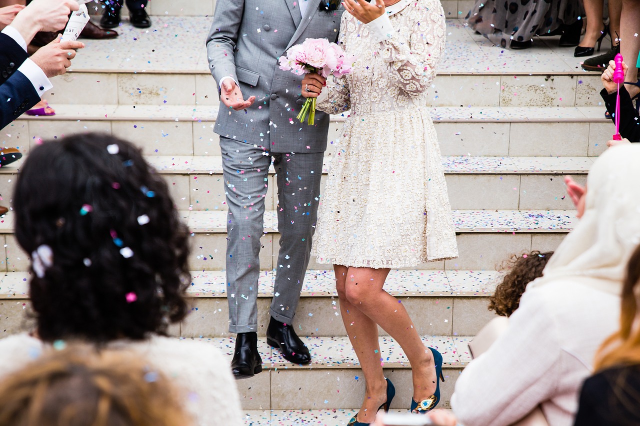 mariés sur un escalier avec invités qui lancent des confettis